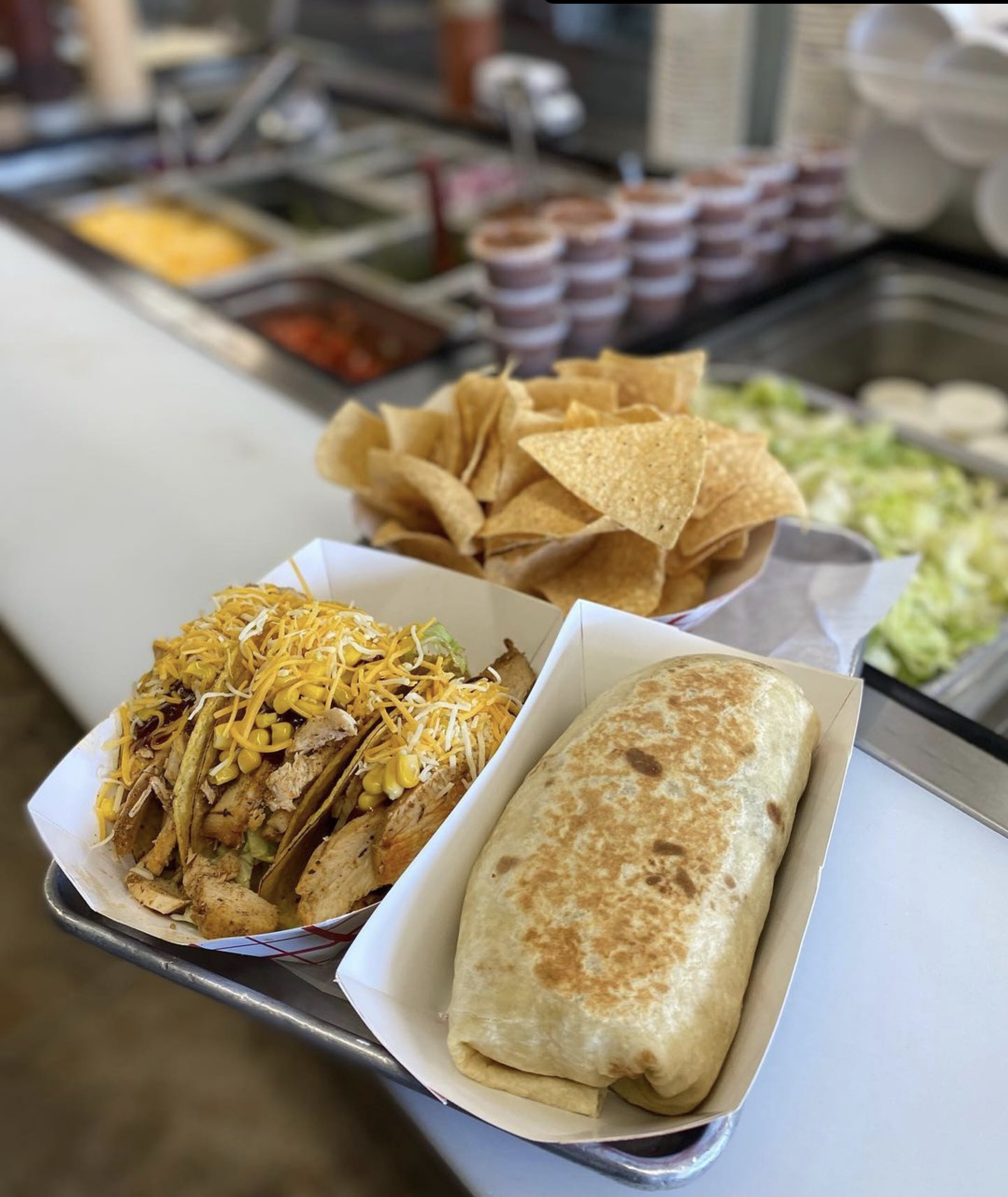 A tray of delicious tacos, nachos and a burrito.